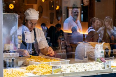 Floransa, İtalya - 10 Mayıs 2025: Turistler sokaklara bakarken, zanaatkar şef vitrinde elle taze makarna hazırlıyor