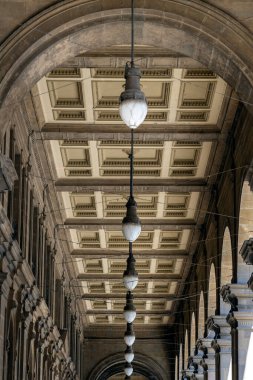 Floransa, İtalya 'da taş kemerli tarihi bir salonda kasalı tavan ve klasik ışıkların simetrik görüntüsü