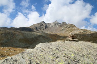 Passo di Gavia zirvesindeki İtalyan Alpleri manzarası. Güneşli bir günde aşağıda güzel tepeler ve bir göl..
