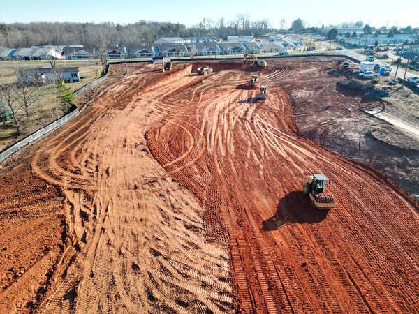 Бульдозеры и штамповщики на стройплощадке занимаются планировкой и выравниванием земли под застройку в Трутмане, шт. Северная Каролина. 