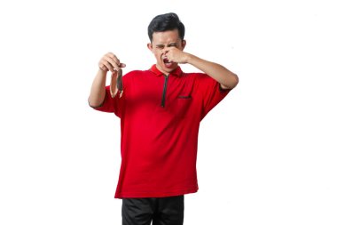 Asian man covers his nose with his hand while holding a smelly banana peel clipart