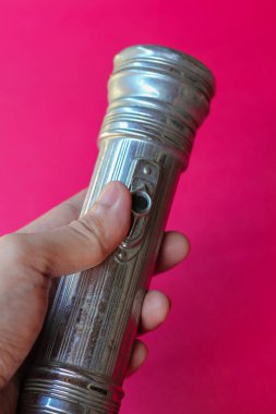 Metal el feneri tutan adam kırmızı arka planda.