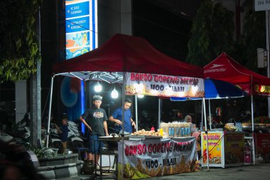 Endonezya, Solo - 8 Aralık 2024: Kızarmış köfte satıcısı yol kenarında bir tezgah kurup müşterilerin gece gelmesini bekliyor..