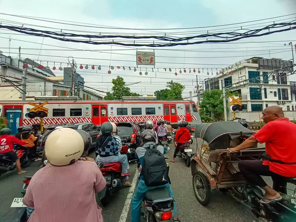 Endonezya, Solo - 11 Aralık 2024: Bir grup araç trenin geçmesini beklerken demiryolu geçidinde durdu.
