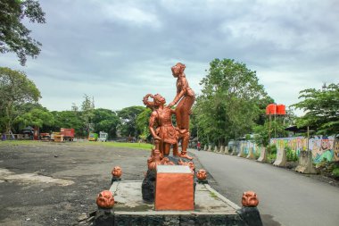 Indonesia, Solo - December 14, 2024: Gatot Kaca statue supporting a beautiful goddess with a background of cloudy skies, located in Sriwedari Park, Solo clipart