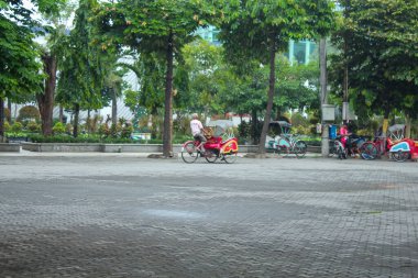 Endonezya, Solo - 14 Aralık 2024: eski bir çocuk taksisi kaldırımlı bir yoldan geçiyor