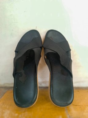 Bir çift siyah sandaletin önünde kalın bir taban ve çapraz kayış tasarımı var..