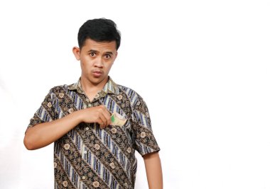 Batik tişört giyen Asyalı adam cebinden para alıyor, beyaz arka planda soyutlanmış.