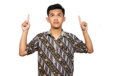 Parang desenli batik kumaş giyen Asyalı adam izole edilmiş beyaz arka planı işaret ediyor.