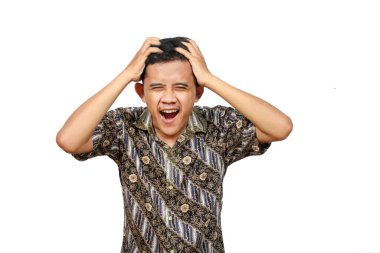 Batik giysili Asyalı bir adam stres ifadesi sergiliyor. İki elini de beyaz arka planda tutuyor.