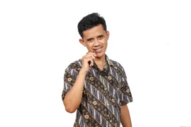 Beyaz arka planda izole edilmiş bardakları ısıran Batik elbiseli Asyalı bir adamın samimi portresi.