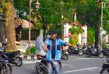 Endonezya, Solo - 22 Aralık 2024: Park görevlileri, tek başına park etmek isteyen motosiklet sürücülerine yol tarifi verdiler