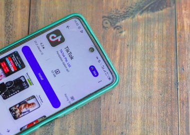 Endonezya, Solo - 26 Aralık 2024: Bir numaralı trend tiktok uygulaması, Android akıllı telefonundaki tiktok simgesi ahşap masa arkaplanı üzerinde