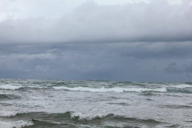 Fırtınalı dalgalar karanlık bir arka planda denize çarpıyor.