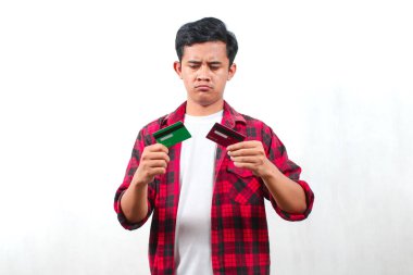 Kareli tişört giyen Asyalı bir adam beyaz arka planda izole edilmiş bir kafa karışıklığının kredi kartı ifadesini taşıyor.