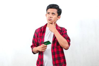 Kareli tişört giyen Asyalı bir adam beyaz arka planda izole edilmiş bir kafa karışıklığının kredi kartı ifadesini taşıyor.