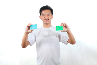 Beyaz t-shirt giyen Asyalı adam kredi kartını beyaz arka planda tutuyor. İş, finans, ekonomi konsepti