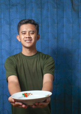 Asyalı adamın elinde mavi perde arkasında neşeli bir ifade var.