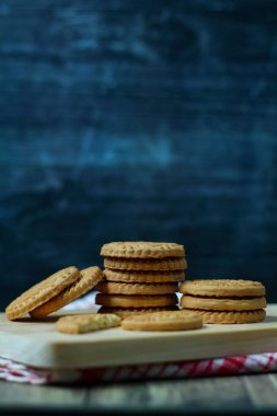 Tahta bir tahtanın üzerindeki lezzetli badem bisküvileri izole edilmiş koyu arkaplan