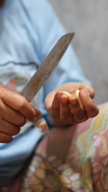 Kadının eli keskin bir bıçakla soğanı soyuyor.