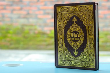 Arapça Kur 'an, Arapça bir dille, yani Kur' an-ı Mübarek, mavi bir sehpanın üzerinde, arkaplanı ise koyu renkli bir dille yazılmıştır. Boşluğu kopyala