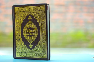 Arapça Kur 'an, Arapça bir dille, yani Kur' an-ı Mübarek, mavi bir sehpanın üzerinde, arkaplanı ise koyu renkli bir dille yazılmıştır. Boşluğu kopyala