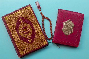 Al Kur 'an ve ahşap boncuklar mavi arka planda izole edilmiş. Dini kavram.