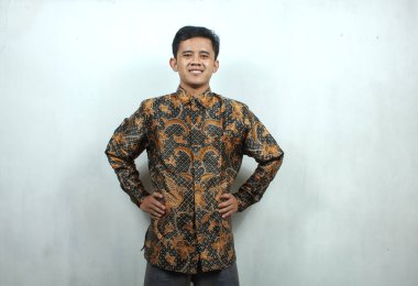 Batik tişört giyen Asyalı adam tatlı tatlı gülümsüyor, beyaz arka planda soyutlanmış.