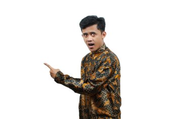 Uzun kollu batik gömlek giyen Asyalı bir adamın portresi. Kameraya bakıyor, parmak yana, izole beyaz arka plan.