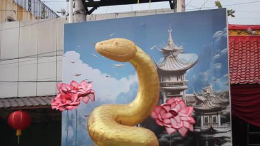 Endonezya, Solo - 26 Ocak 2025: Lotus çiçeği süslemesiyle sergilenen altın yılan heykeli