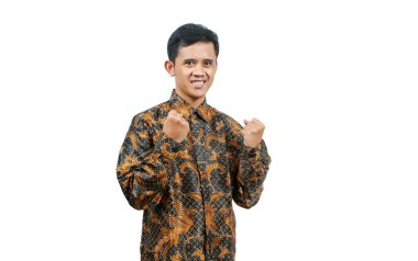 Batik tişört giyen Asyalı adam zafer kutlaması yapıyor, beyaz arka planda izole edilmiş.