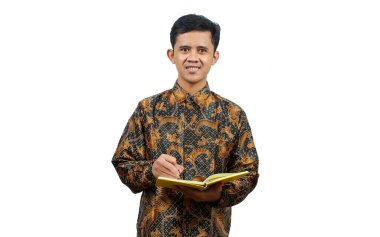 Batik tişört giyen genç öğrenciler, öğretim görevlisinin öğrettiği bilgileri not alıyorlar.