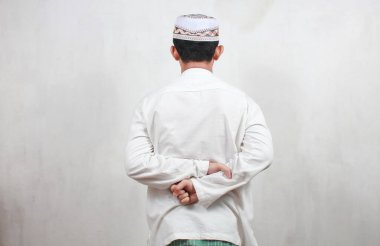 Müslüman Asyalı adam geriye dönük durmalı ve ellerini arkada tutmalı.