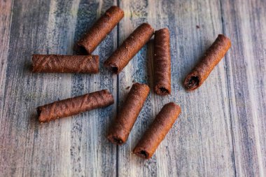 Tahta arka planda izole edilmiş bir avuç lezzetli çikolata astarı.