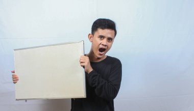 Siyah tişört giyen Asyalı bir adam beyaz arka planda protesto işareti taşıyor.