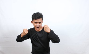 Asyalı kızgın adam beyaz arka planda yumruk saldırısı yapıyor.