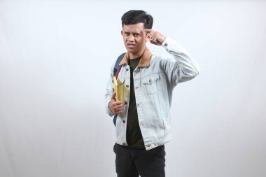 Kot ceket giyen Asyalı bir adam çanta ve kitap taşıyarak ciddi bir düşünce belirtisi gösteriyor. 