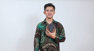 Batik gömlekli Asyalı adam elinde Cava Blangkon şapkası tutuyor.