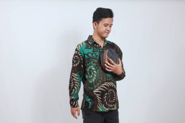 Batik gömlekli Asyalı adam elinde Cava Blangkon şapkası tutuyor.