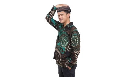 Batik gömlek giyen Asyalı bir adam portresi ve beyaz arka planda izole edilmiş Cava Blangkon şapkası.