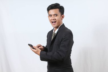 Siyah takım elbiseli Asyalı bir ofis çalışanı elinde akıllı telefon tutarak müşteriye pazarlık mesajı gönderiyor, beyaz arka planda izole edilmiş. İş ve teknoloji kavramı.