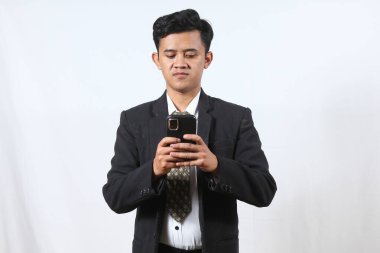 Siyah takım elbiseli Asyalı bir ofis çalışanı elinde akıllı telefon tutarak müşteriye pazarlık mesajı gönderiyor, beyaz arka planda izole edilmiş. İş ve teknoloji kavramı.