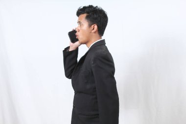 Asyalı erkek işadamı şirketin hisse senedi sözleşmesi hakkında cep telefonundan konuşuyor.