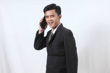 Asyalı erkek işadamı şirketin hisse senedi sözleşmesi hakkında cep telefonundan konuşuyor.