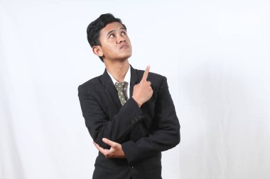 Asyalı iş adamı beyaz arka planda sahiplenerek ve parmağını yukarı kaldırarak düşünüyor.