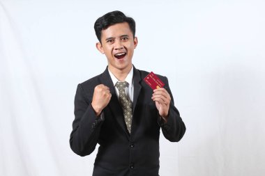 Genç iş adamı, kredi kartını beyaz arka planda tutarken çok heyecanlı.