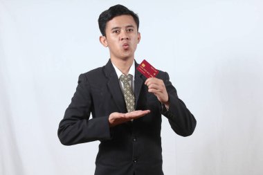 Asyalı işadamı gülümseyerek beyaz arka planda izole edilmiş kredi kartını tutuyor.