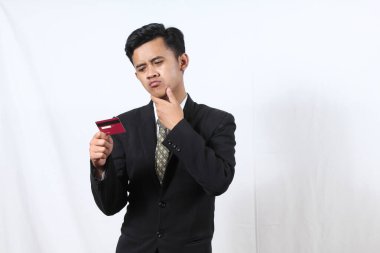 Siyah takım elbiseli Asyalı işadamı kredi kartını beyaz arka planda tutarken şaşkın hissediyor