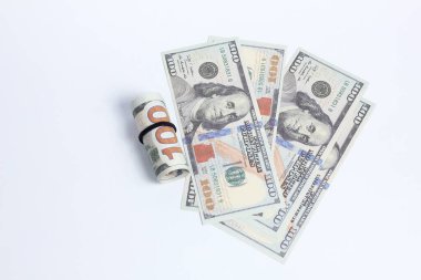 Beyaz arka planda izole edilmiş, dağınık banknotların yanında 100 dolarlık banknotları kapat.