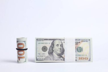100 dolarlık banknotlar beyaz arka planda diğer para yığınlarının yanında.